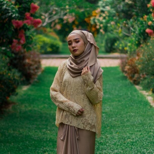 woman wearing grey hijab standing in a garden, plated founder's photo